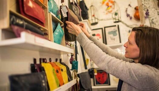 A woman reaching for a brown handbag off a shelf