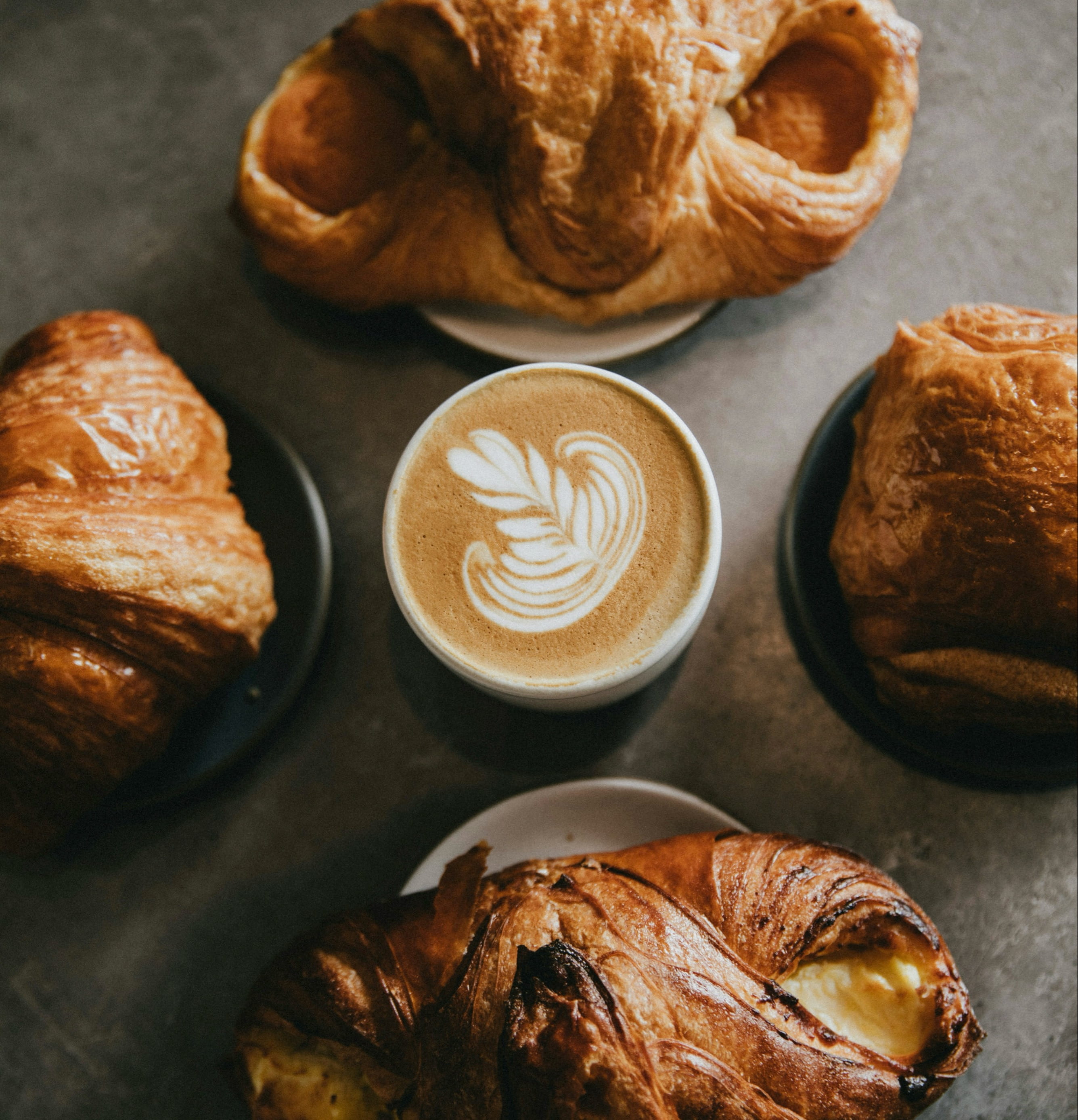 Four croissants with a coffee in the middle