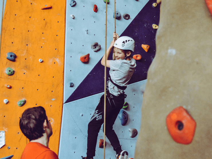 A child on a climbing wall with a helmet on