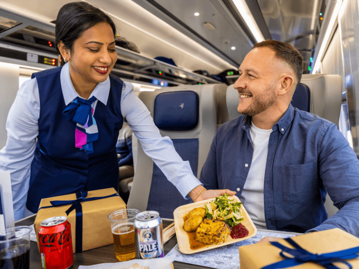 A TransPennine Express host serving a Holiday Nutless Roast to a passenger onboard